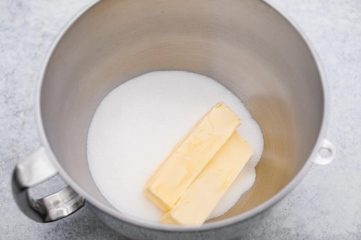 Overhead shot of butter and sugar in the bottom of a stand mixer bowl. 