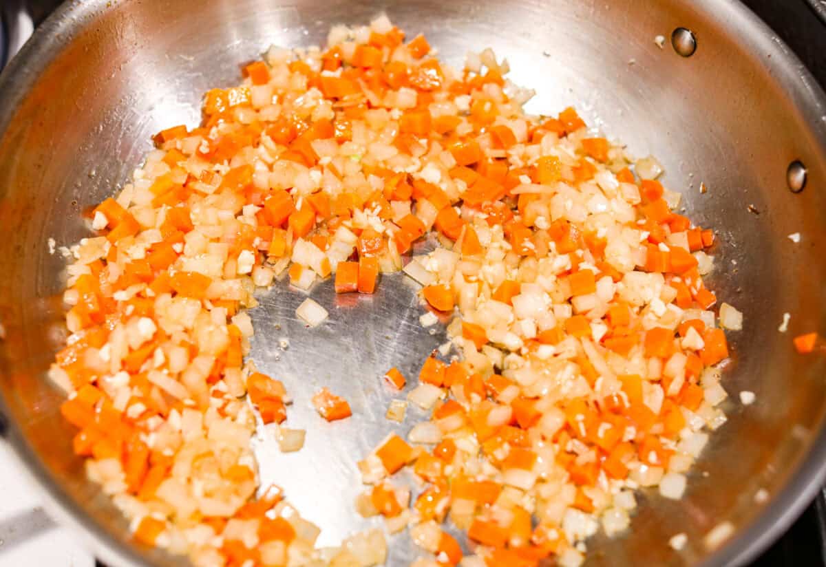 Overhead shot of veggies sautéing in a skillet. 