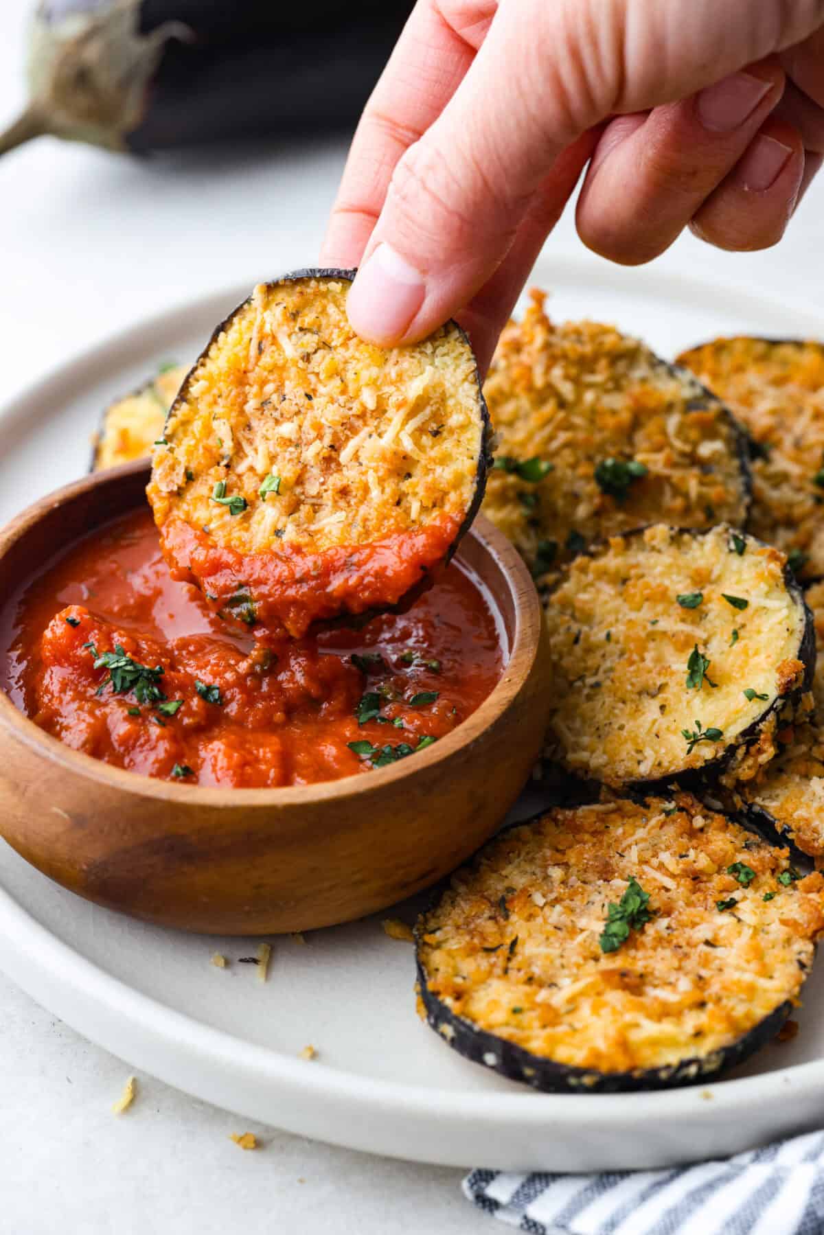 Close up shot of someone dipping an ai fryer eggplant chip into marinara sauce. 