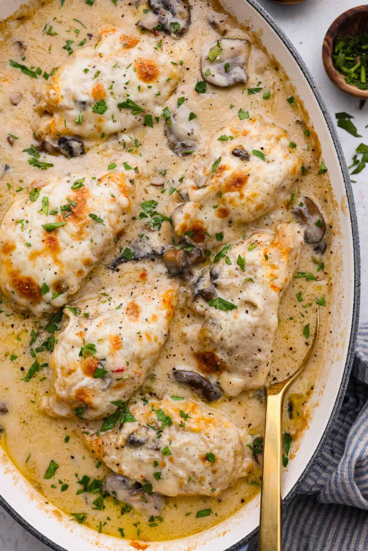 Overhead shot of chicken gloria in a baking dish with gold serving spoon. 