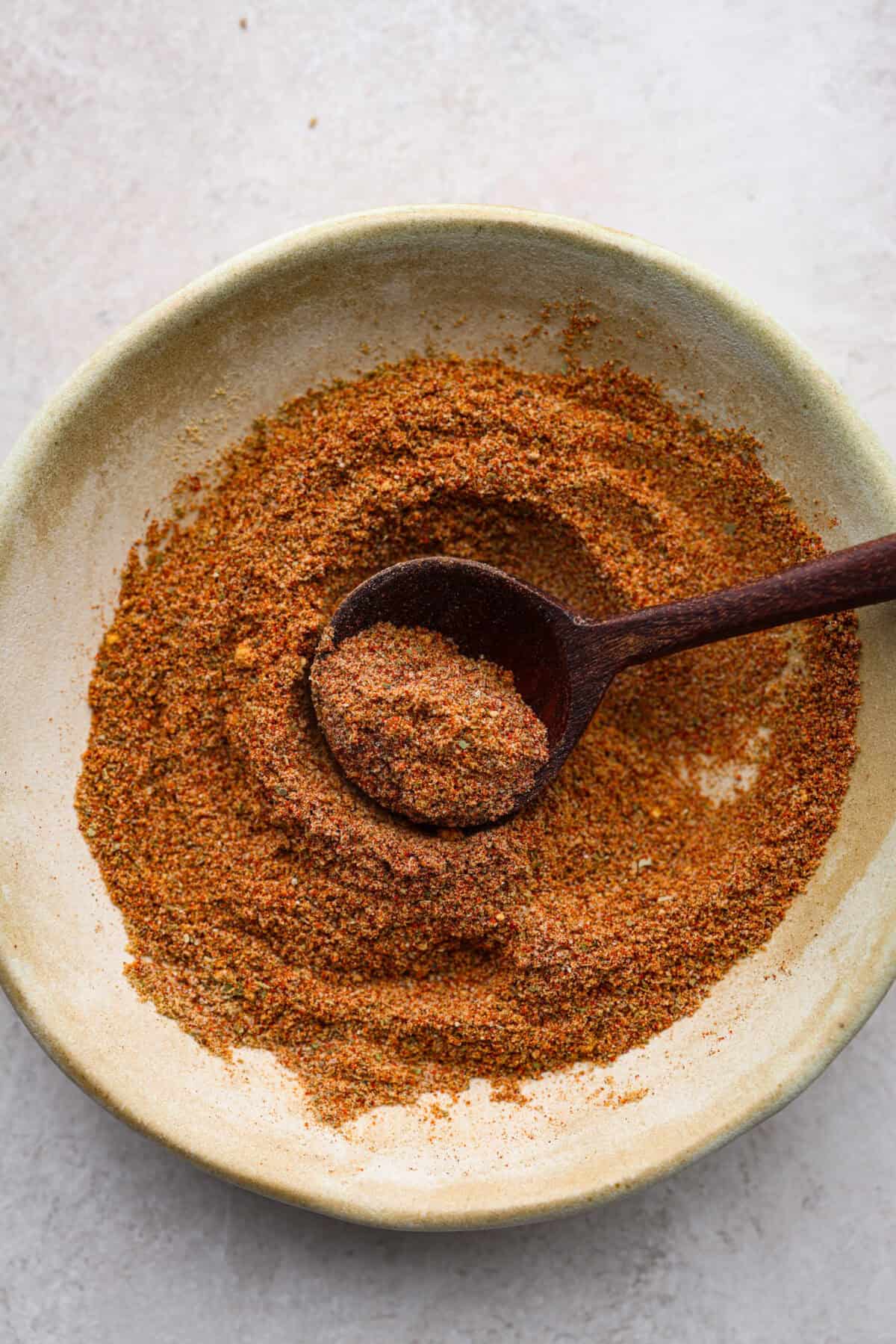 Overhead shot of homemade old bay seasoning mixed together on a plate with a wooden spoon. 