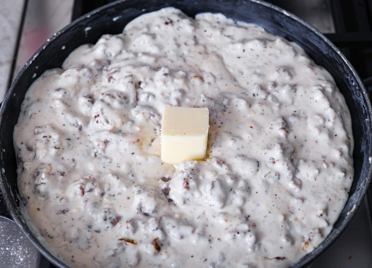 Overhead shot of the creamy gravy and meat mixture with a cube of butter in the middle. 