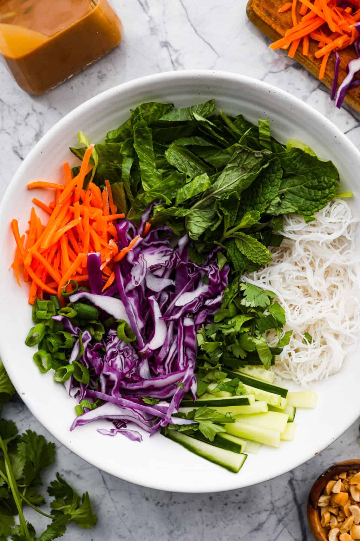 Close up shot of all of the ingredients added to a spring roll bowl, but they haven't been mixed together. 