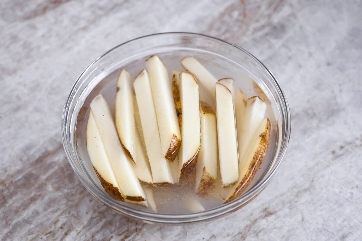 Overhead shot of sliced potatoes in cold water. 