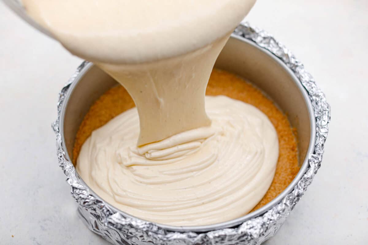 Pouring cheesecake mixture into a pan.