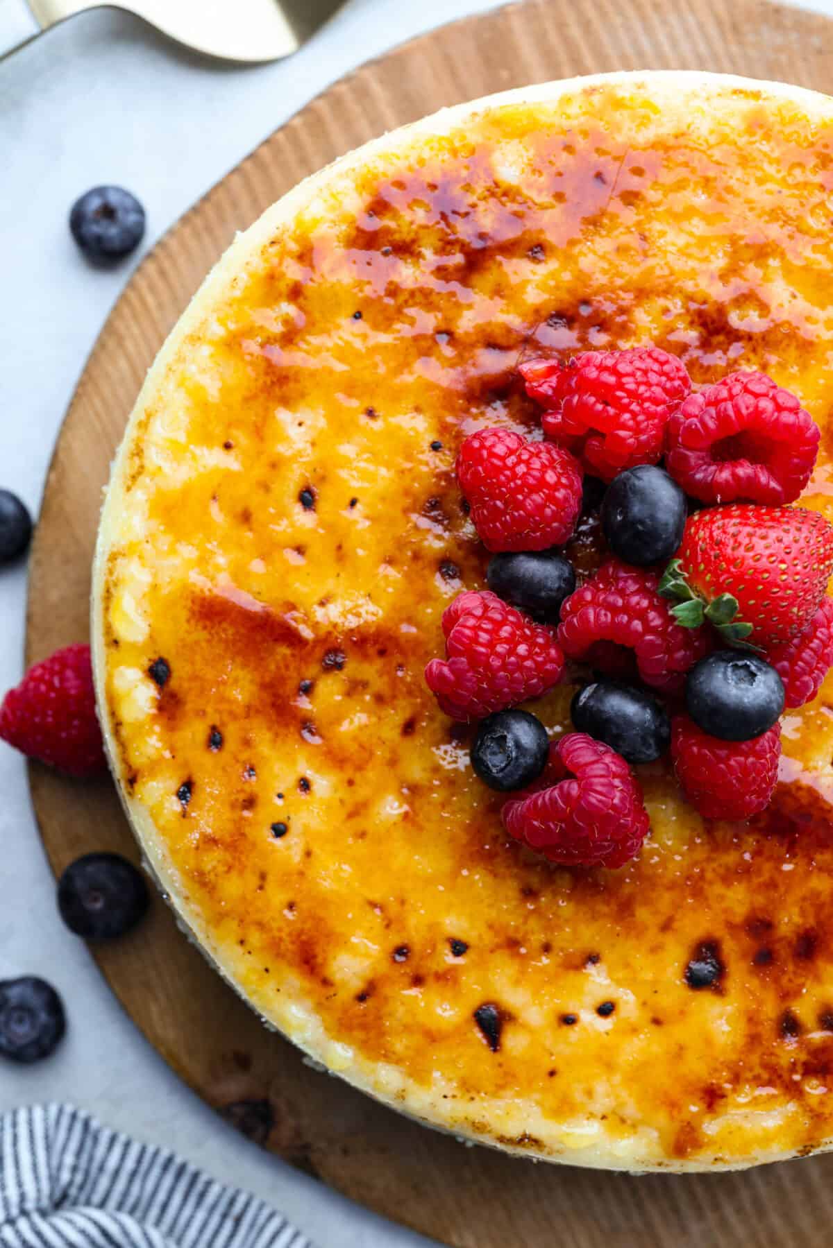 Overhead shot of creme brûlée cheesecake with berries on top. 