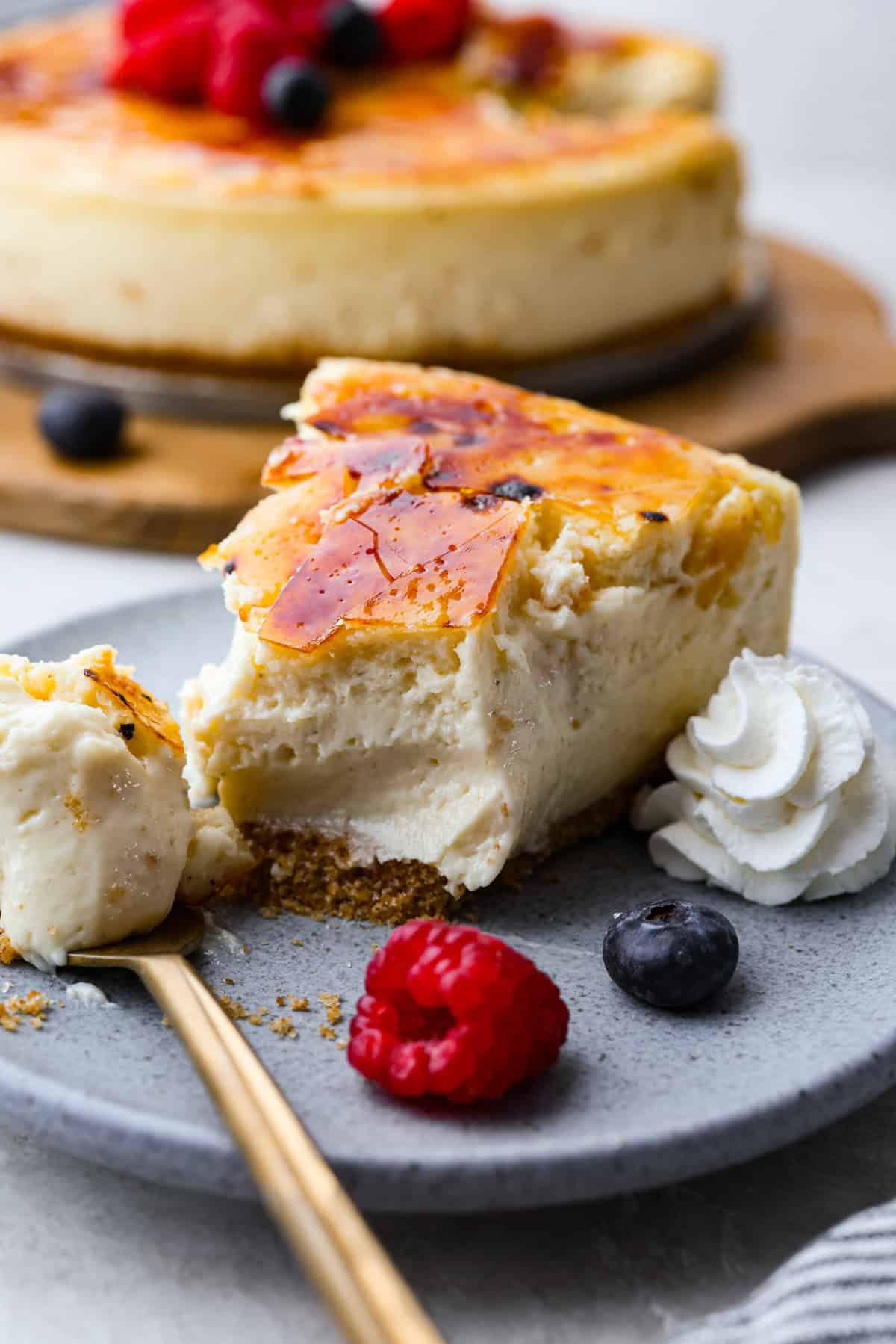 Creme brulee cheesecake on a plate with whipped cream.