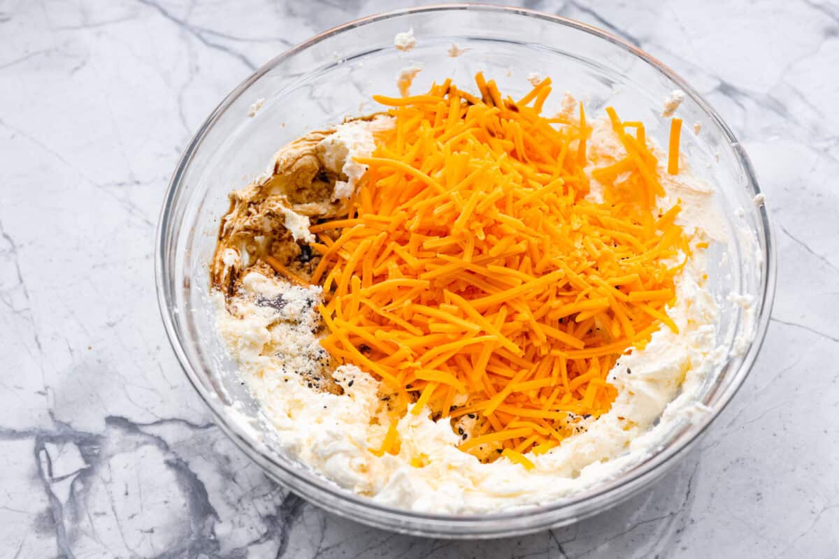 Overhead shot of the cream cheese with cheddar cheese, garlic powder, onion powder, Worcestershire sauce and seasoning in a bowl. 