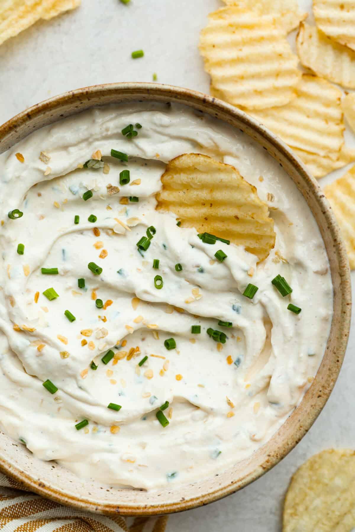 Overhead shot of sour cream and onion dip with a chip sticking out of it. 